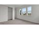 Bedroom with three large windows, carpet, and a sliding closet door for ample storage at 6608 Quest St, St Cloud, FL 34771