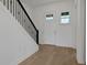 Bright foyer with light hardwood floors, a white door, and a staircase with a black metal railing at 6608 Quest St, Saint Cloud, FL 34771