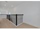Hallway with wood floors, black metal railings, and bright, recessed lighting at 6608 Quest St, St Cloud, FL 34771