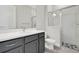 A bathroom with white counters, a gray vanity, and glass shower at 6612 Quest St, St Cloud, FL 34771