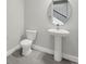 A powder room featuring a toilet and pedestal sink beneath an oval mirror at 6612 Quest St, St Cloud, FL 34771
