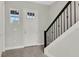 Welcoming foyer with gray floors, white door, and a staircase with black iron railing at 6612 Quest St, St Cloud, FL 34771