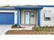Inviting front entrance with a covered porch, blue trim, manicured landscaping, and a blue garage door at 6612 Quest St, St Cloud, FL 34771