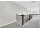 Upstairs hallway view with gray carpet, white walls, and a black iron railing with decorative accents at 6612 Quest St, St Cloud, FL 34771