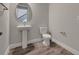 Modern powder room featuring a pedestal sink, tile flooring, and a round mirror, ideal for guests at 6616 Quest St, St Cloud, FL 34771