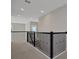 Upstairs hallway features neutral walls, carpet, and black iron railing on the landing at 6616 Quest St, Saint Cloud, FL 34771