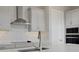 Close-up of a kitchen featuring stainless steel appliances, white marble backsplash, and modern light fixtures at 6616 Quest St, St Cloud, FL 34771