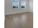 A bedroom with light colored laminate flooring, white walls, and two large windows at 15615 Vetta Dr, Montverde, FL 34756
