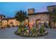 Stunning stone facade with a circular driveway and decorative fountain at dusk, offering an elegant and inviting entrance at 15615 Vetta Dr, Montverde, FL 34756