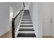 A staircase with white risers and black treads and a black handrail at 15615 Vetta Dr, Montverde, FL 34756
