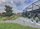Beautifully landscaped backyard with stone accents, a lush lawn, and an enclosed patio area at 518 Narrow View Ln, Groveland, FL 34736