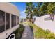 Landscaped backyard featuring a stone pathway, white arbor, palm tree, and a screened porch at 803 Camino Del Rey Dr, The Villages, FL 32159