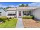 Charming single-story home featuring a well-manicured lawn, lovely front garden, and a welcoming red front door at 803 Camino Del Rey Dr, The Villages, FL 32159