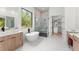 Bright modern bathroom featuring a soaking tub, glass-enclosed shower, and dual vanities at 16909 Crete Way, Bella Collina, FL 34756