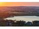 Picturesque view of a lakeside community at sunset with a golf course and luxury homes on the horizon at 16909 Crete Way, Bella Collina, FL 34756