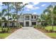 Stately two-story home boasts a symmetrical design, an elegant balcony, lush landscaping, and a paver driveway at 16909 Crete Way, Bella Collina, FL 34756