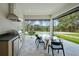 A lovely outdoor kitchen and dining area overlooks a stunning pool and forested backyard at 16909 Crete Way, Bella Collina, FL 34756