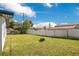 Spacious, grassy backyard enclosed by a white fence; firepit in yard at 2030 Leisure Dr, Winter Haven, FL 33881