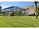Beautiful backyard featuring a screened-in lanai and a lush green lawn with tropical plants at 210 Westcott Ct, Deland, FL 32724