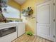 Convenient laundry room with washer, dryer, overhead shelving, and natural light from the window at 4088 Kingsley St, Clermont, FL 34711