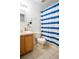 Bathroom features toilet, shower with blue-and-white striped curtain, and vanity with cabinet at 1836 Ridge Valley St, Clermont, FL 34711