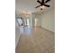 Open-concept living area with tile flooring, ceiling fan, and a view of the front entrance with decorative glass door at 24124 Robinwood St, Leesburg, FL 34748