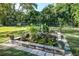 Backyard features a manicured lawn, beautiful plants, mature trees, and a small water feature at 1405 Hilltop Dr, Mount Dora, FL 32757