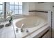 Bright bathroom featuring a soaking tub with tiled surround and window at 1405 Hilltop Dr, Mount Dora, FL 32757