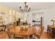 Bright dining room features a chandelier, wood table and chairs, and flows to other rooms at 1405 Hilltop Dr, Mount Dora, FL 32757