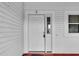 A white front door with a window panel and visible smart lock features on a light colored house at 956 Chula Ct, The Villages, FL 32159
