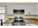 Stainless steel microwave and oven stove top with granite countertops and white cabinetry at 956 Chula Ct, The Villages, FL 32159