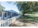 Landscaped backyard with a screened patio and white fence at 2030 Alfredo Ave, The Villages, FL 32159