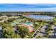 Aerial view of the community featuring a pool, tennis courts, clubhouse, lake, and parking area on a sunny day at 22204 Caledonia Dr, Leesburg, FL 34748