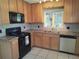 Functional kitchen with light wood cabinets, black appliances, and tile backsplash at 405 N Rhodes St, Mount Dora, FL 32757