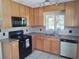 Charming kitchen featuring wooden cabinets, a black oven range, microwave, and stainless-steel dishwasher at 405 N Rhodes St, Mount Dora, FL 32757