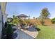 Well-manicured backyard featuring an outdoor dining set, fire pit, and lush landscaping at 1132 Maynard Path, The Villages, FL 32163