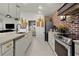 Bright kitchen featuring an island, stainless steel appliances, and a brick accent wall at 1132 Maynard Path, The Villages, FL 32163