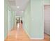 Hallway with wood flooring and light green walls leading to dining area and bathroom at 26701 Bimini Dr, Tavares, FL 32778