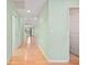 Long hallway with light green walls and wood flooring, leading to a bright living area at 26701 Bimini Dr, Tavares, FL 32778