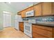 Well-lit kitchen with oak cabinets, sleek black countertops, and white appliances at 26701 Bimini Dr, Tavares, FL 32778