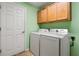 Laundry room with light green walls, white washer/dryer, and wooden cabinets at 26701 Bimini Dr, Tavares, FL 32778