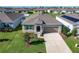 Aerial view of home with front lawn, landscaped garden, neutral paint, two car garage, and concrete driveway at 1089 Fig St, Tavares, FL 32778