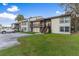 Exterior view of condo building with wood balconies, green grass, and a parking lot at 22103 Sandalwood Dr # 103, Wildwood, FL 34785