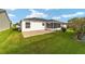 Backyard featuring a sunroom, green grass, and a small patio area at 2552 English Ivy Cir, The Villages, FL 32162