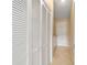 Hallway features a closet with louvered doors and tile flooring, with a white door at the end at 2552 English Ivy Cir, The Villages, FL 32162