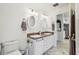 Bright bathroom with double vanity, granite counters, matching oval mirrors, and marble flooring at 36729 Alaqua Ct, Eustis, FL 32736