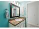 Bright blue bathroom with granite countertops, stylish framed mirror, and neutral colored cabinetry at 36729 Alaqua Ct, Eustis, FL 32736