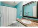 Bathroom with granite countertops, stylish mirror, walk in shower, and bright turquoise walls at 36729 Alaqua Ct, Eustis, FL 32736