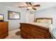 Comfortable bedroom with wood furniture, a ceiling fan, and a view of a large mirror at 36729 Alaqua Ct, Eustis, FL 32736