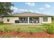 View of the back of the property, with a covered lanai, landscaped yard, and patio with seating at 36729 Alaqua Ct, Eustis, FL 32736
